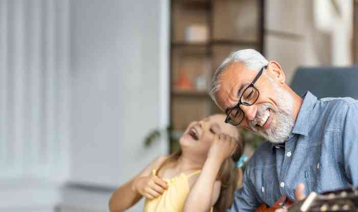 Grandfather and young granddaughter happily playing guitar